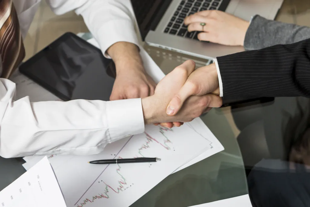 Handshake over financial documents, symbolizing Integrity 1 Solutions' investigative expertise.