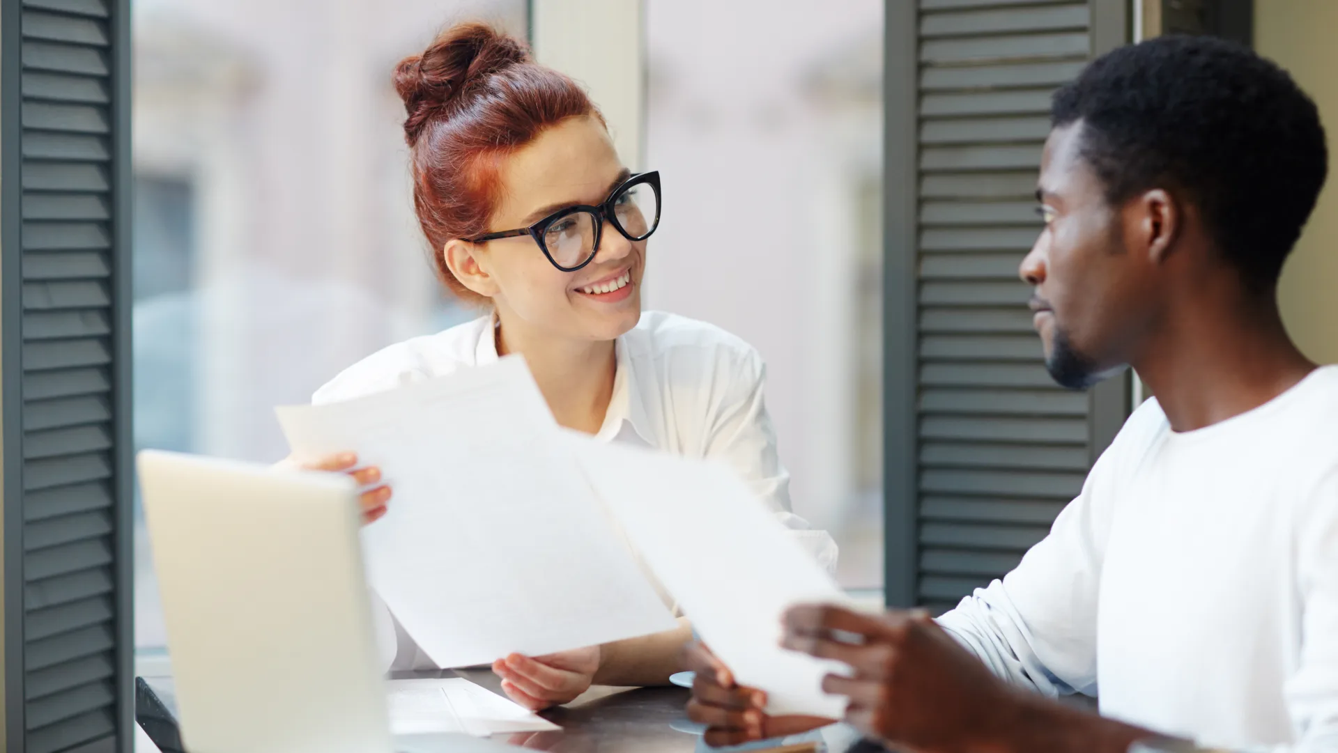 Smiling business professional reviewing documents with a colleague during a background check process